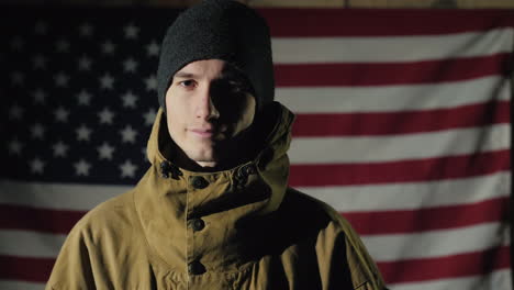 the silhouette of a man -- he looks at the american flag on the brick wall the view from behind