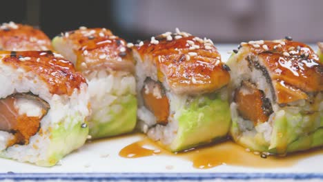 cook pouring sushi set with sauce while preparing dish in modern kitchen