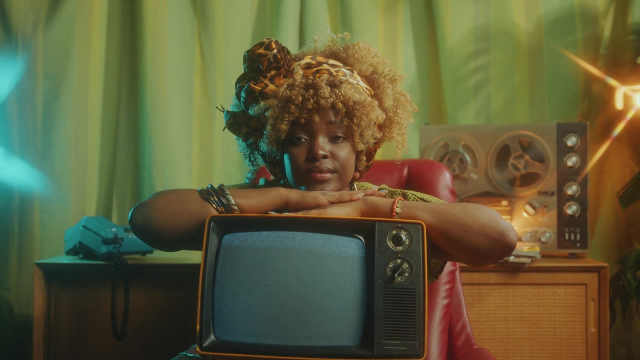 Ritratto di una bellissima donna di colore con una vecchia TV in uno studio retrò