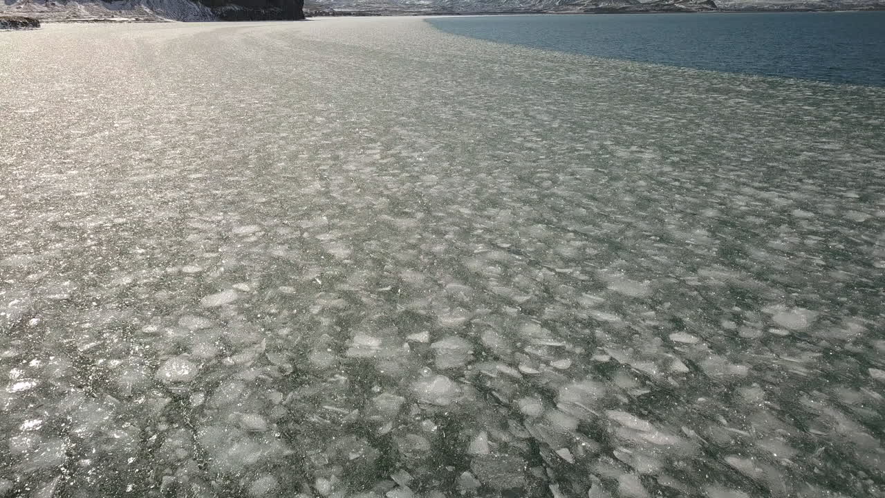 배경에 산이 있는 아이슬란드의 셀포스 지역 근처 해빙을 향해 아래로 기울어지는 시네마틱 드론 샷