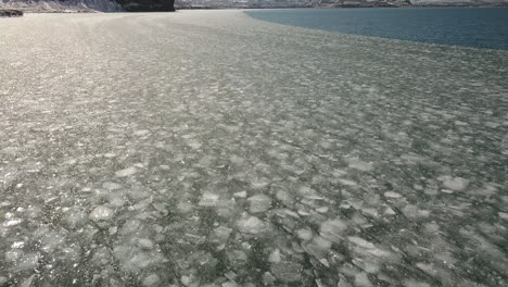 disparo cinematográfico de drones inclinándose hacia el hielo marino cerca del área de selfoss en islandia con montañas en el fondo