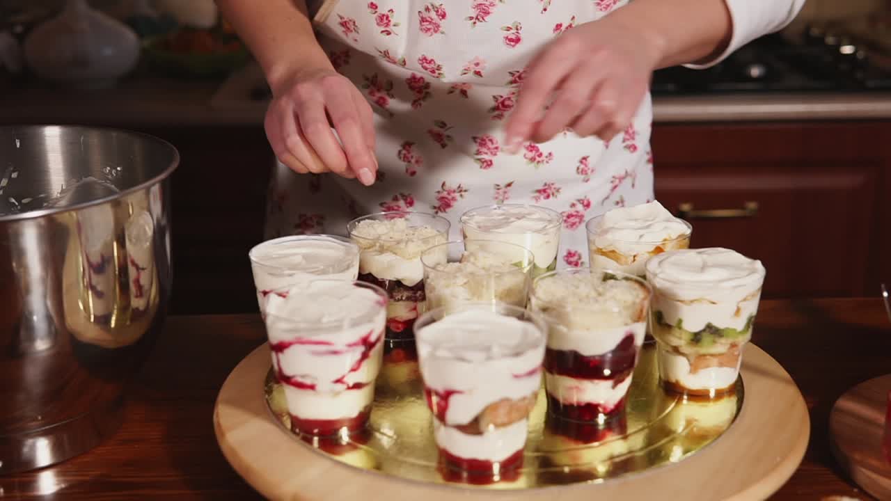 여자가 컵에 층층으로 디저트를 준비하고 있습니다.