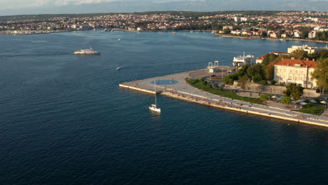 Sailboat-And-Ferry-In-The-Old-Town-Of-Zadar-At-Sunset-In-Croatia---aerial-drone-shot