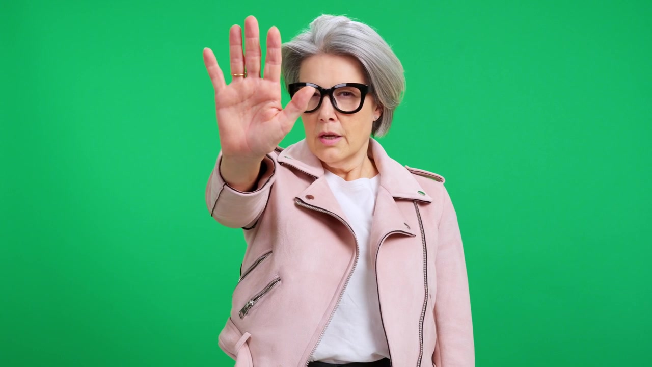 Serious Mature Woman Making a Stop Gesture Against Green Screen