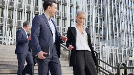 business professionals walking down stairs outside modern office building