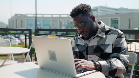 hombre trabajando en una computadora portátil en un café al aire libre
