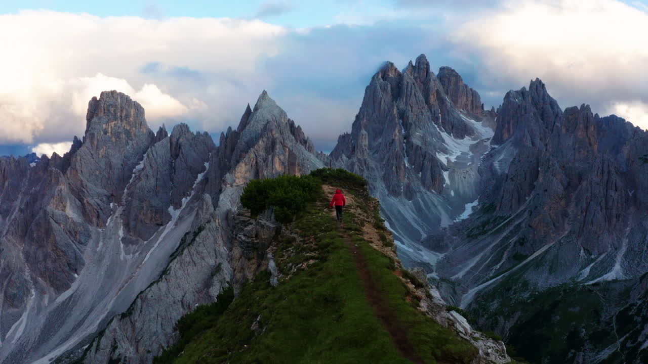 hombre caminando al acantilado de dolomitas en italia, revelando un paisaje épico