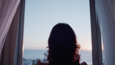 happy old woman opening curtain enjoying early morning sunrise at home feeling peaceful freedom relaxing on retirement vacation looking at beauiful ocean view