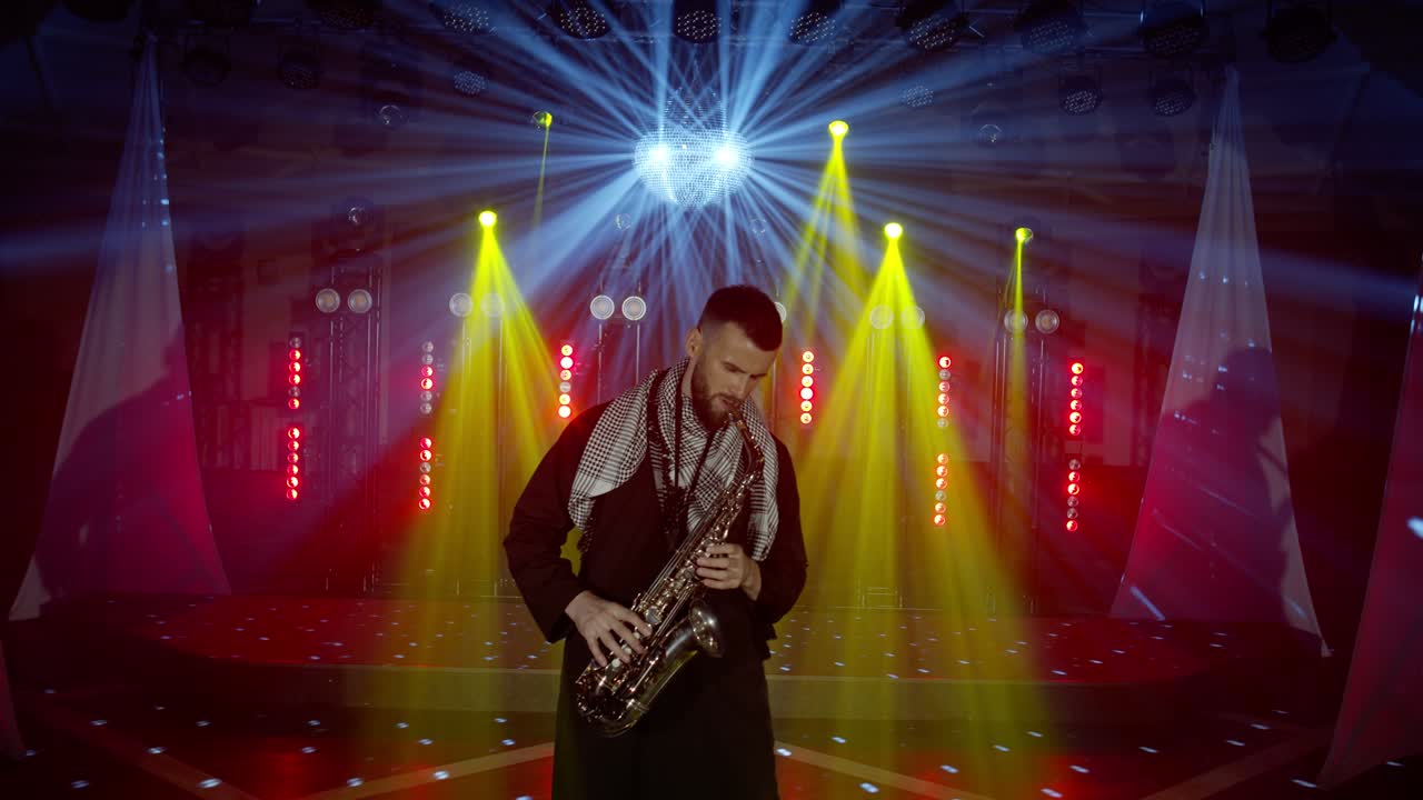 actuación en vivo del saxofonista hombre con saxofón, bailando en el escenario del músico de concierto con luces