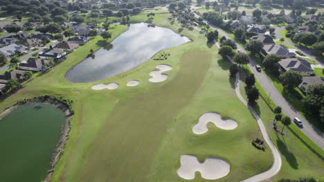 Slow-rising-drone-shot-of-lush-green-golf-course-in-Florida-senior-living-community-during-sunrise