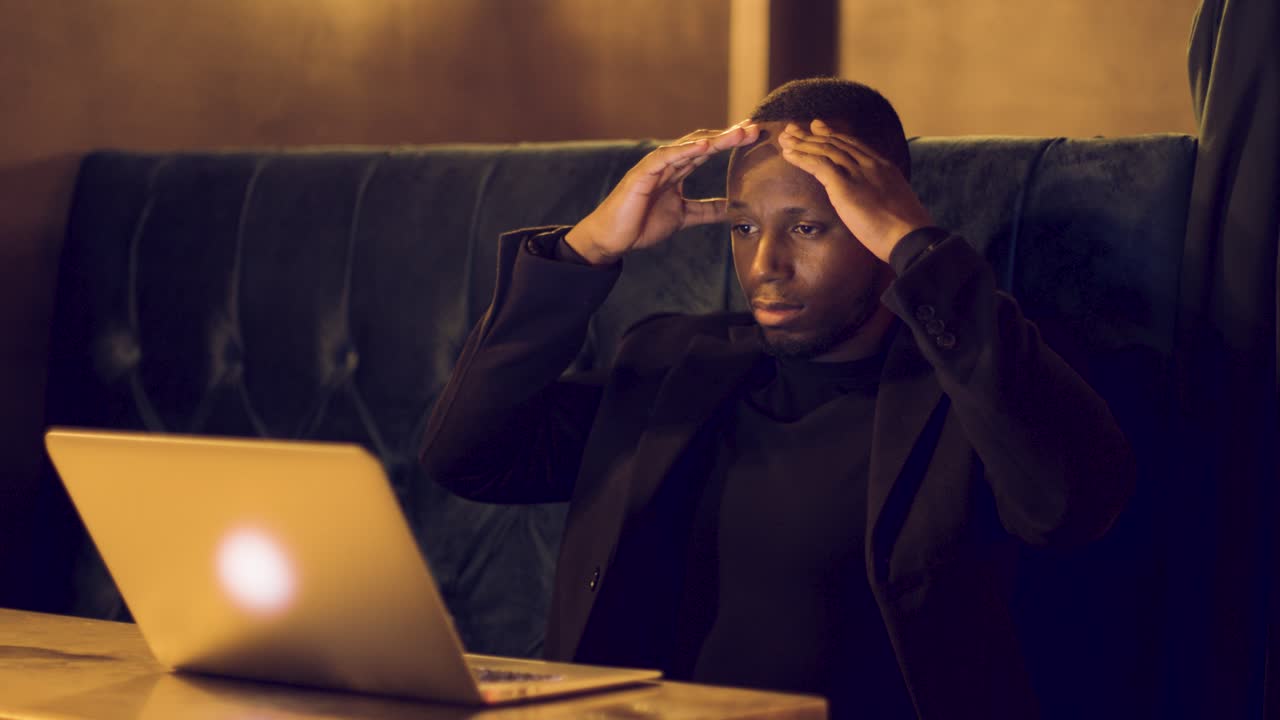Professional male working remotely on a laptop feeling stressed in a caf?