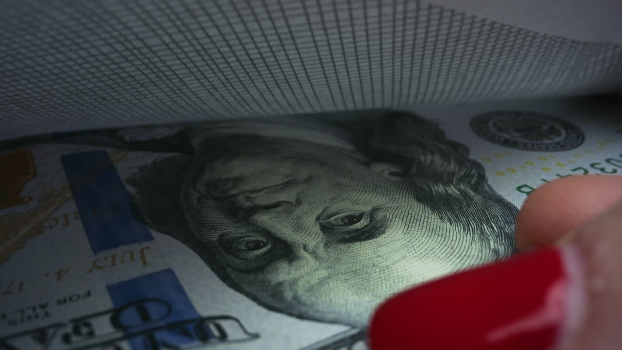 인식할 수 없는 여성이 미국 달러 현금을 봉투에 넣고 있습니다.