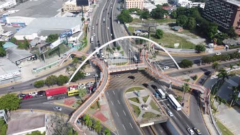 Top-view-of-drone-flying-over-the-main-street-maximo-gomez-in-the-city-of-santo-domingo,-light-traffic-with-cars-waiting-for-traffic-light