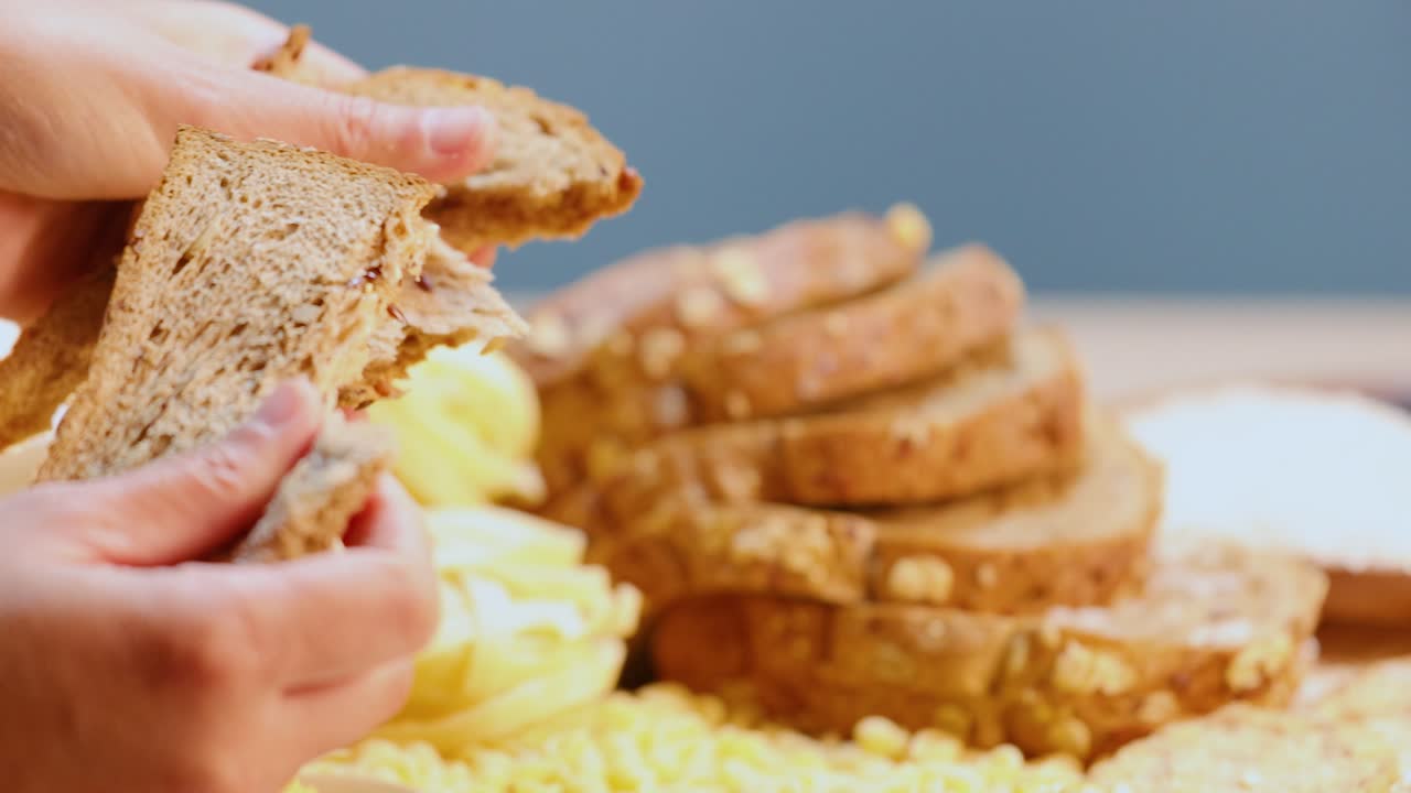 Hands tearing whole wheat bread in a bright kitchen environment with a focus on texture and detail