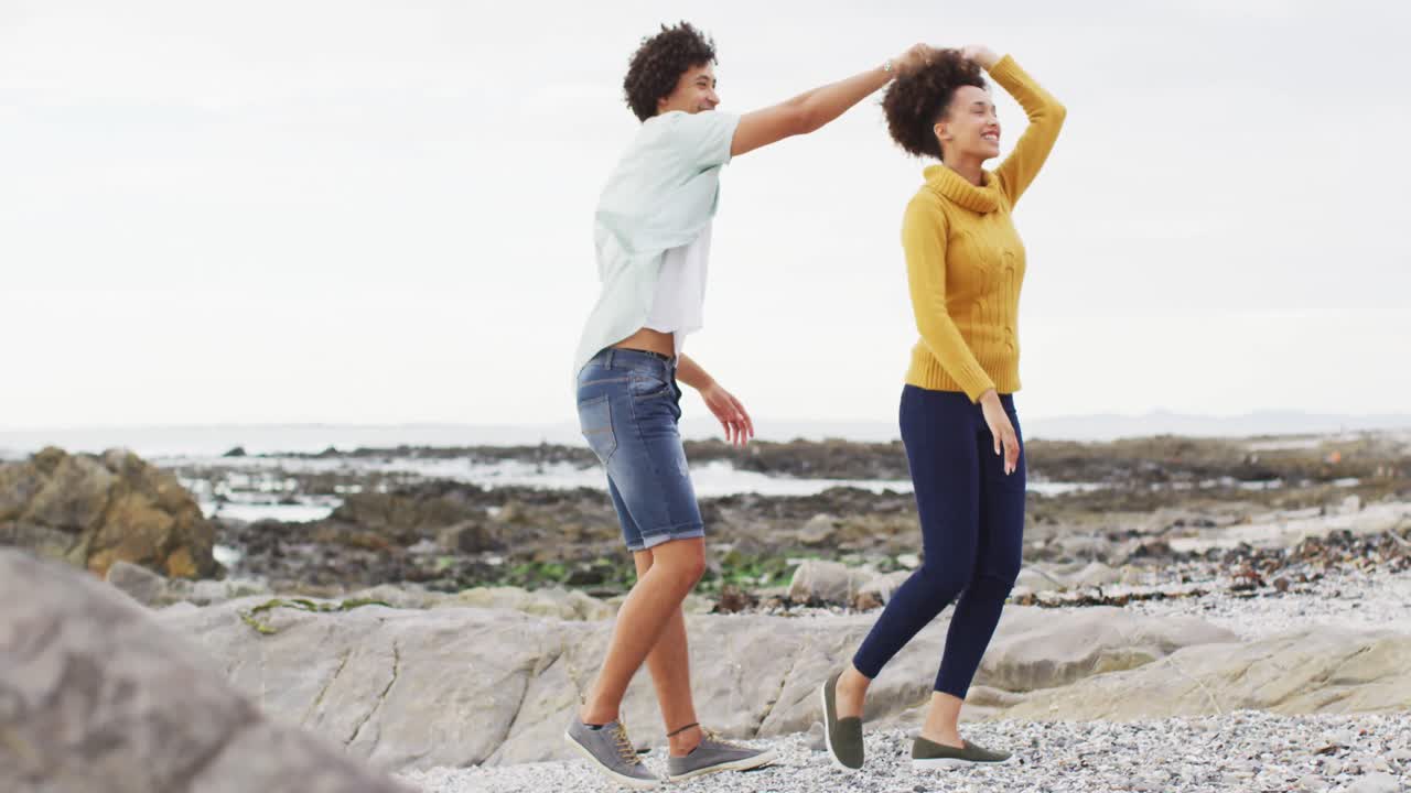 pareja afroamericana bailando juntos en las rocas cerca del mar