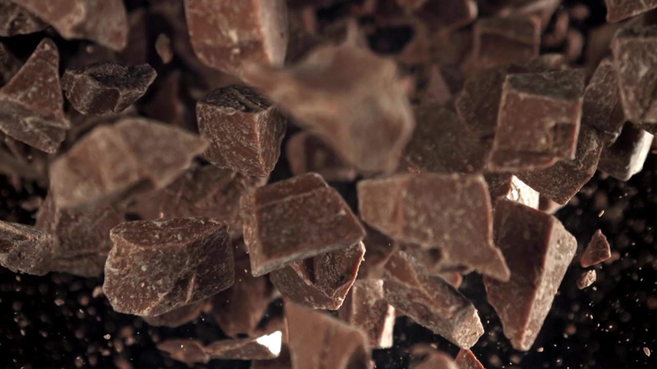 Pezzi di cioccolato che cadono al rallentatore su sfondo scuro