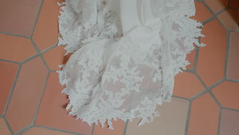 Lace-wedding-dress-train-gracefully-spread-on-terracotta-tiled-floor