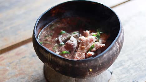 sopa de fideos de cerdo servida en una cáscara de coco