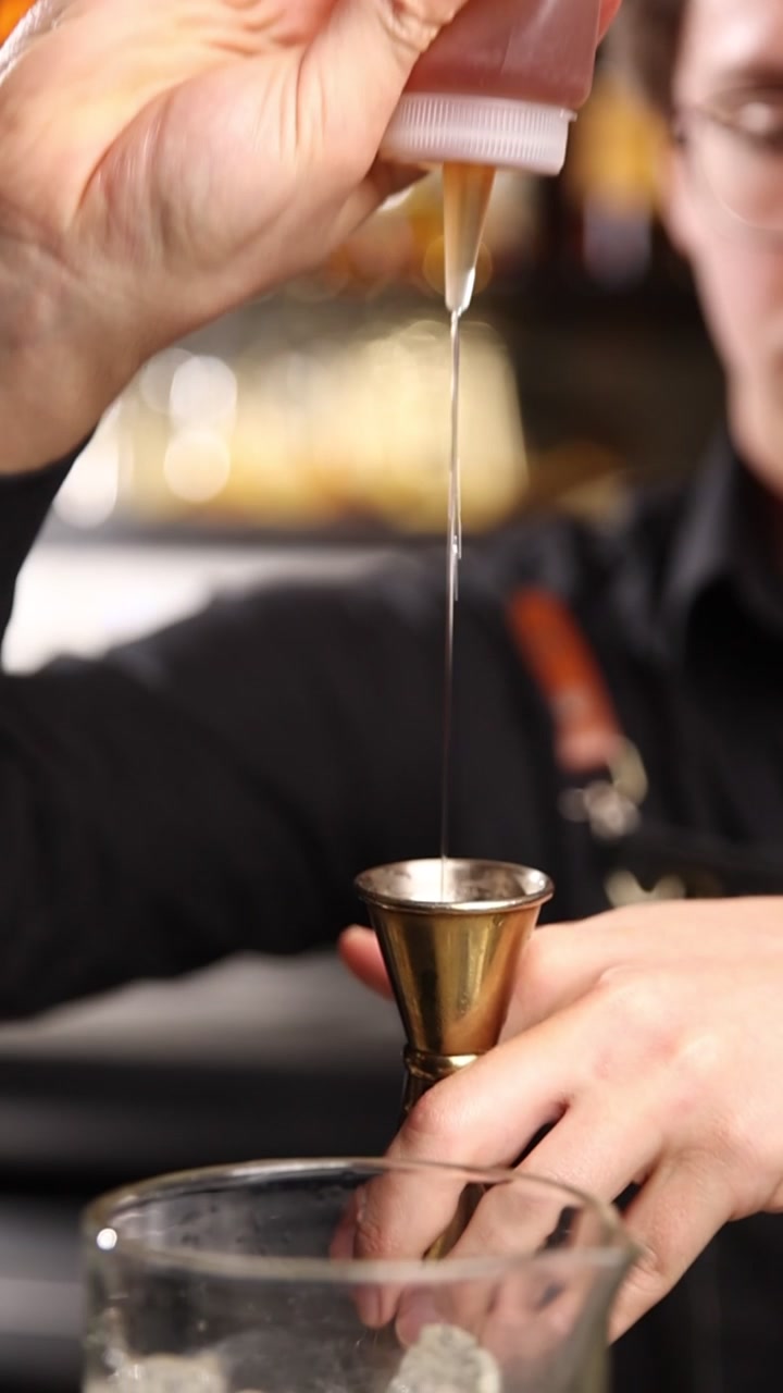 Barman professionista che versa sciroppo in un jigger per un cocktail