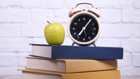 alarm clock, apple, and books