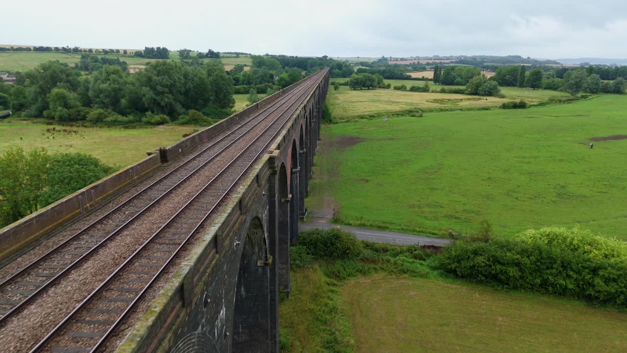 Cinematic drone orbit aerial footage of Harringworth railway viaduct bridge architecture spanning rural green wetlands Corby England United Kingdom