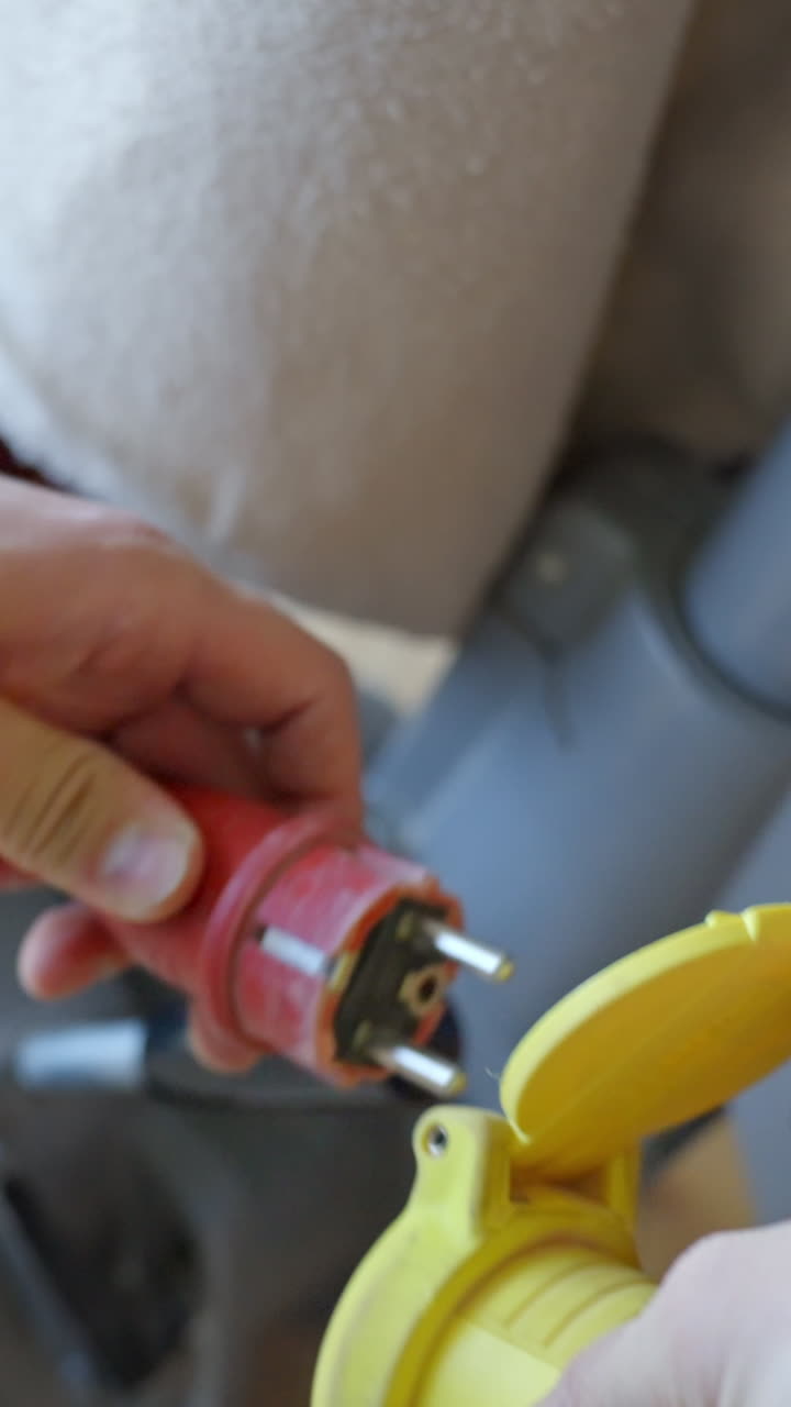 Close-up vertical shot of a red plug securely connected to a bright yellow Power Outlet.