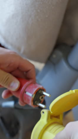 close-up vertical shot of a red plug securely connected to a bright yellow power outlet.