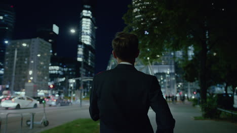 following shot of a man in suit walking alongside road while returning home during evening time