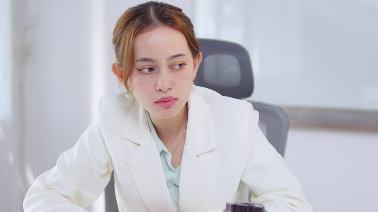 A woman in a business setting expresses contemplation during an important meeting.