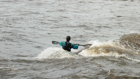 kayaker on the ottawa river surfing the waves created by the rapids of the flood waters