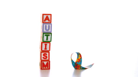 awareness ribbon falling beside blocks spelling autism