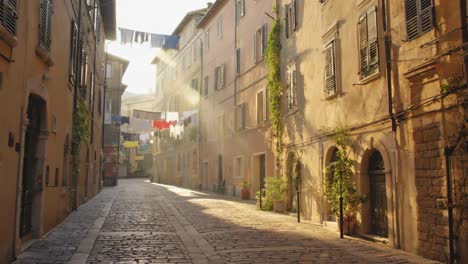 sunlight illuminates clothes hanging across a narrow cobblestone street, creating an idyllic scene of a peaceful morning in a traditional town