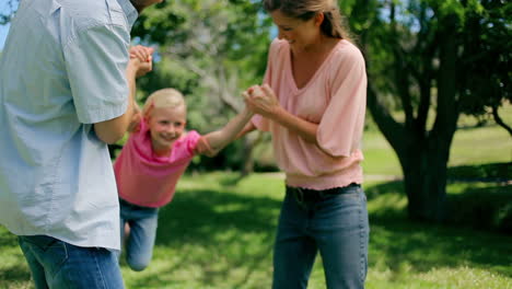 Niña-Siendo-Balanceada-Hacia-Adelante-Y-Hacia-Atrás-Por-Sus-Padres-Que-La-Sostienen-De-Los-Brazos