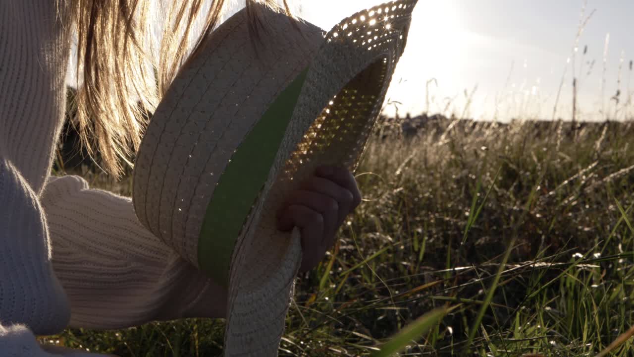 Woman sitting in sunset with straw hat medium shot