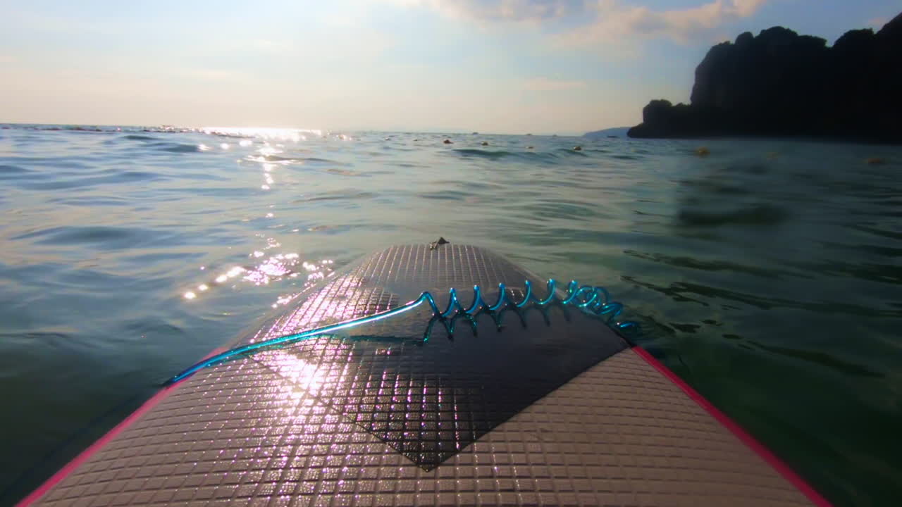 POV da tavola da surf, sole contro il mare blu con scogliere sullo sfondo a Railay, Thailandia, Asia, in 60fps cinematografici