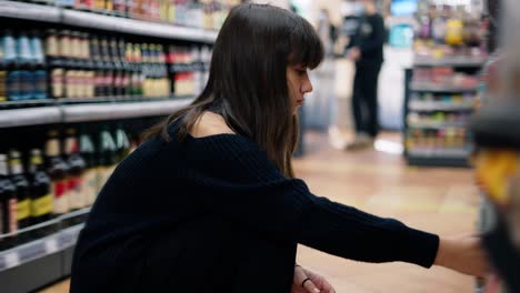 Close-up-footage-of-a-girl-in-the-store-taking-product-from-the-lower-shelf