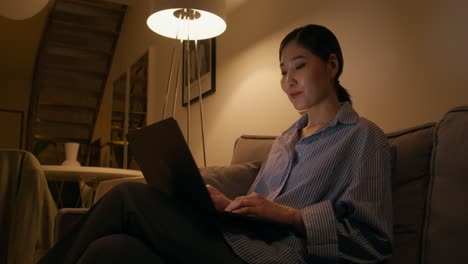 mujer trabajando en la computadora portátil por la noche en casa
