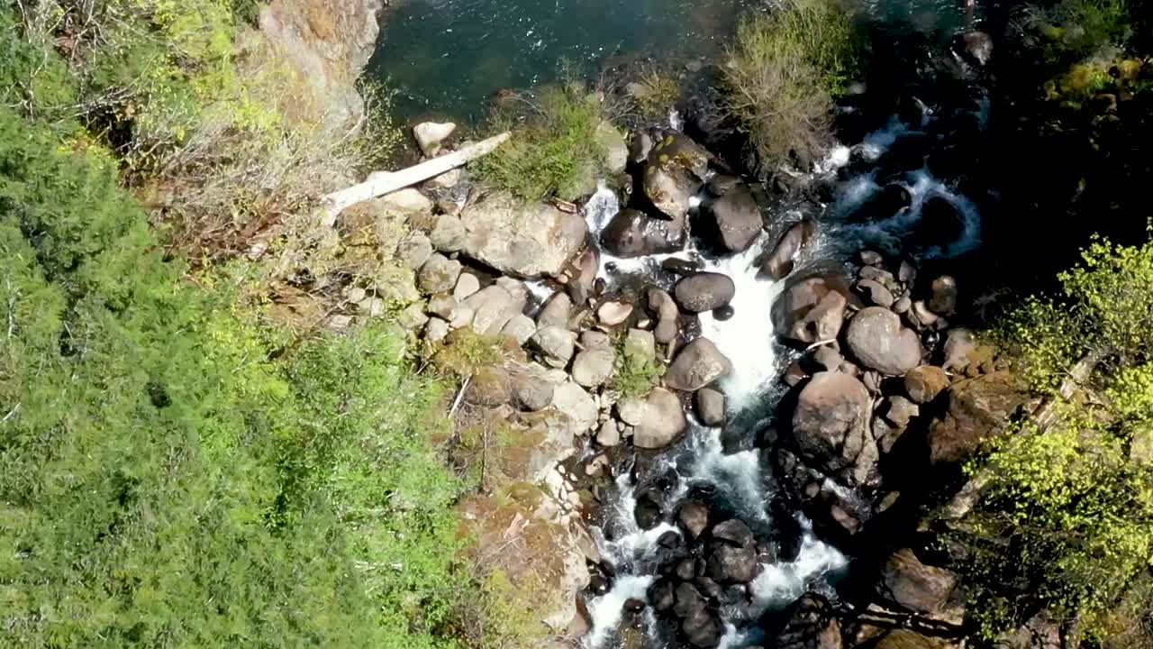 imágenes de drones mirando hacia abajo mientras se mueve con el flujo de agua sobre una caída de agua de dos niveles en las cataratas de coquille