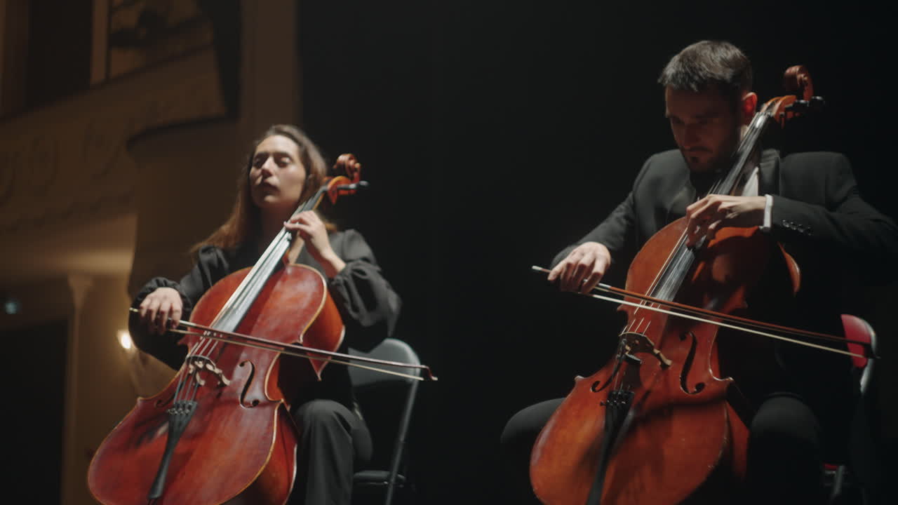 los violonchelistas están tocando en la escena de la vieja orquesta de la ópera en el teatro o la sala filarmónica