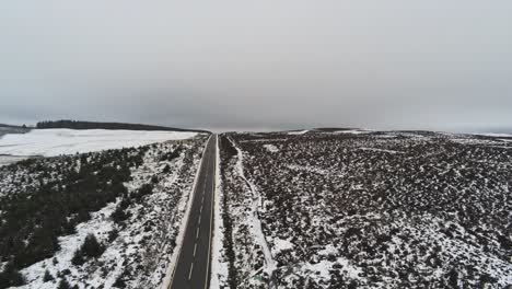 Lange-Straße-Antenne-In-Die-Ferne-über-Hochland-Verschneite-Landschaft-Moore-Absteigend-Erschossen