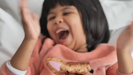 little girl laughing happily in bed