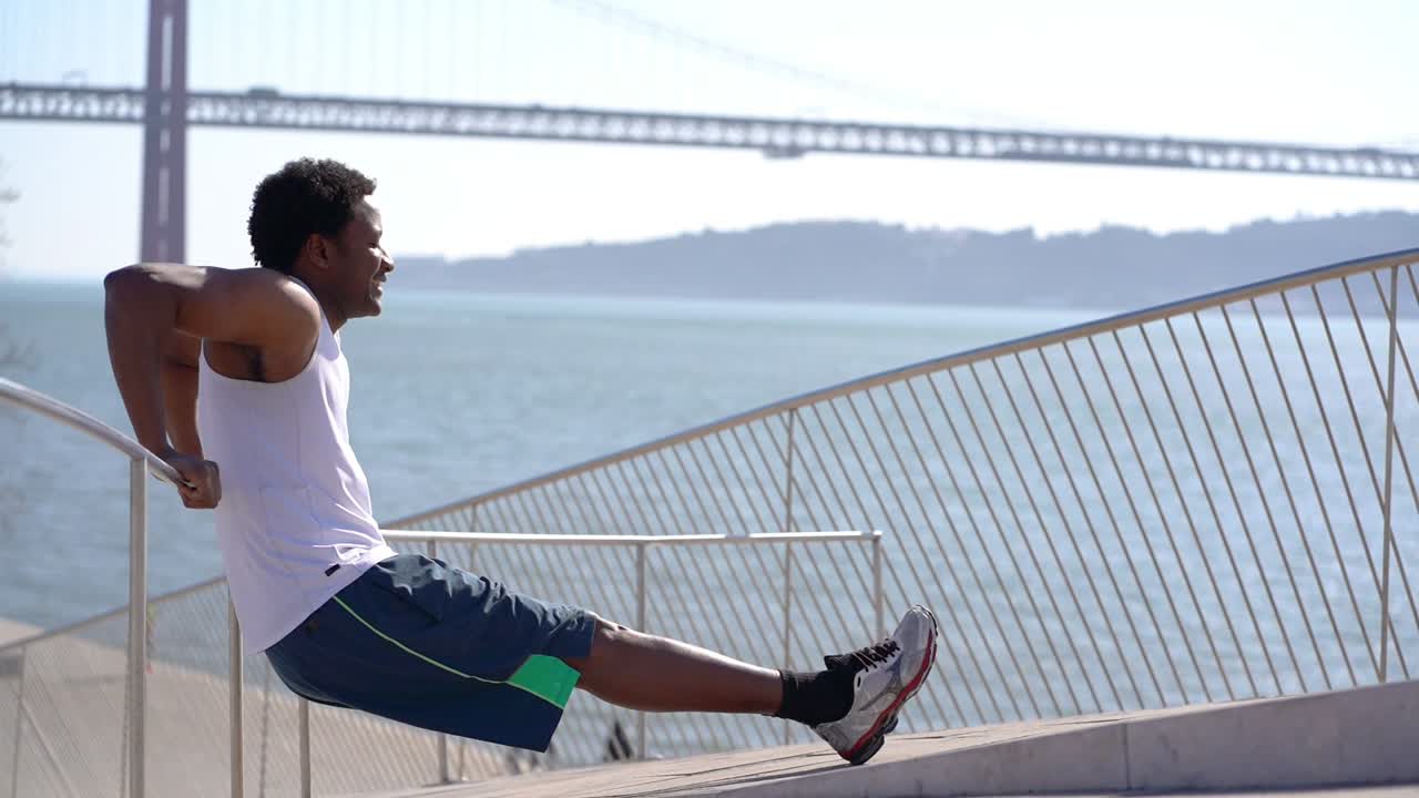 Smiling athletic man exercising on bridge