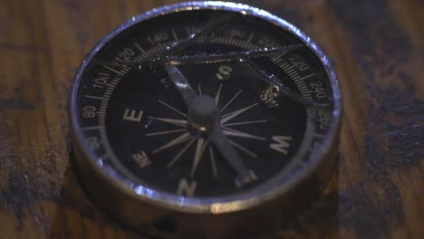 compass arrow moving on different direction while lying on the wooden table - close up shot