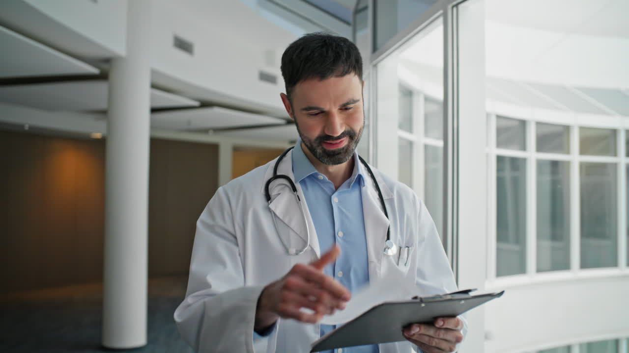 Smiling practitioner looking clipboard in hospital closeup. Happy worker going