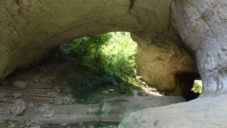 fly through drone shot of the opening of phodna cave, right under the natural arch called gods bridge, located in a geological park in karlukovo, bulgaria