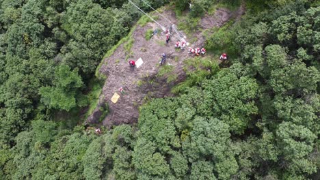 niños con cascos participan en un descenso por cuerda desde un acantilado como parte de una actividad de campamento de verano