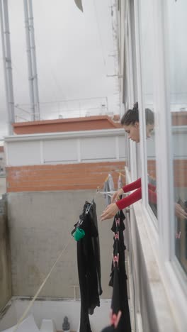 woman drying clothes from apartment window