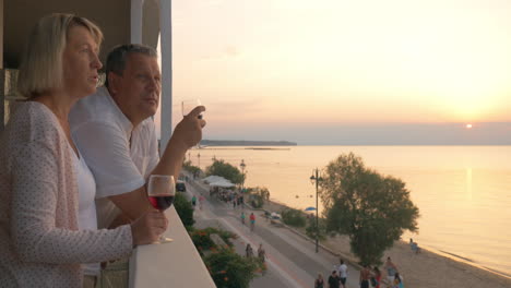 couple drinking wine and looking at resort from balcony