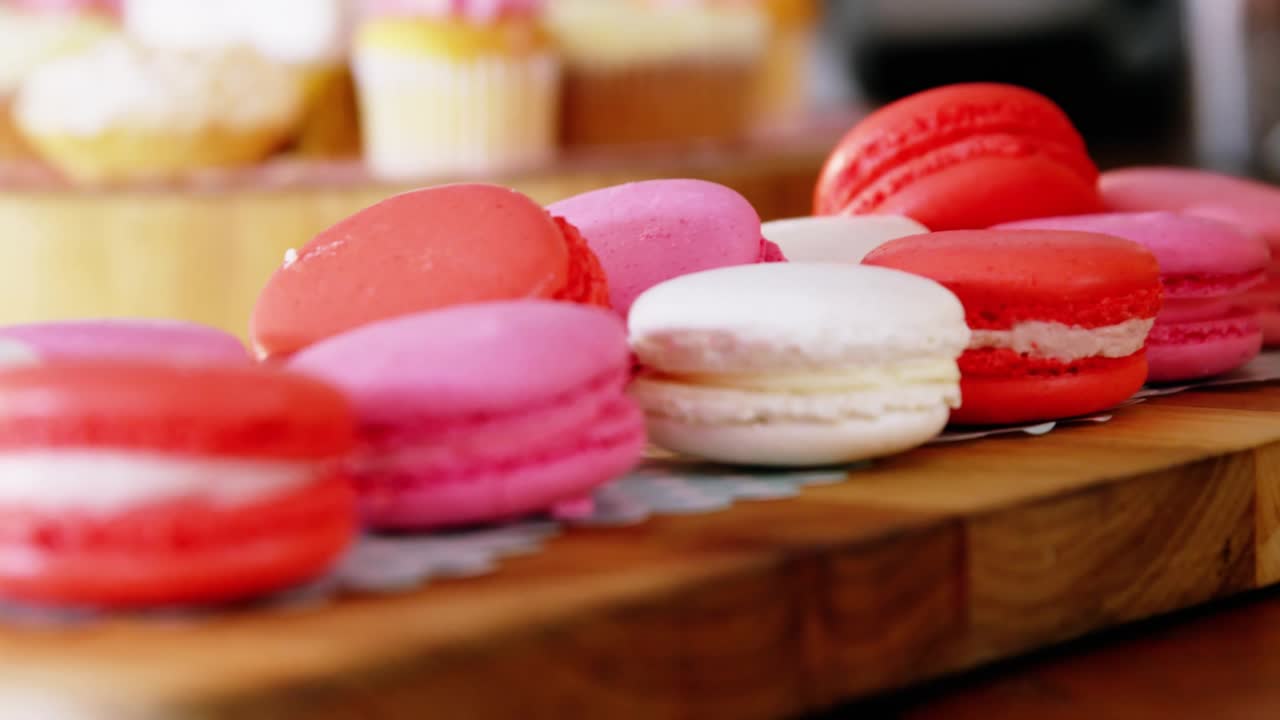 Colorful macarons on wooden board, sparkles drifting and lens flare sweeping, enhancing pastel hues