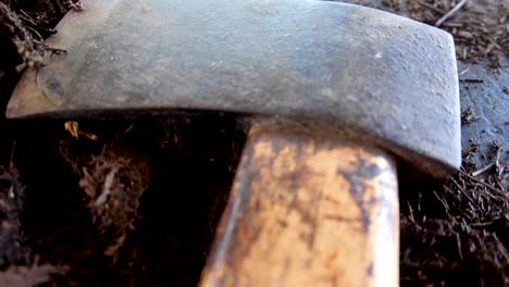 an axe with a wooden handle laying on a woodworkers bench top covered in wood chipping in the workshop, slow pan from bottom to top